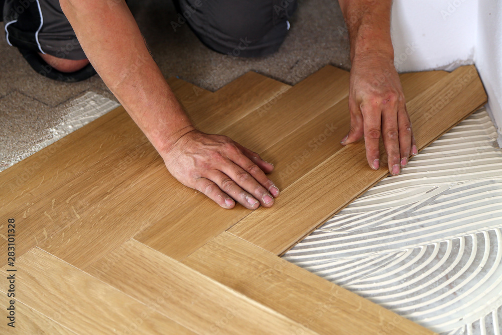 Worker laying parquet flooring. Worker installing wooden laminate flooring Worker laying parquet flooring. Worker installing wooden laminate flooring