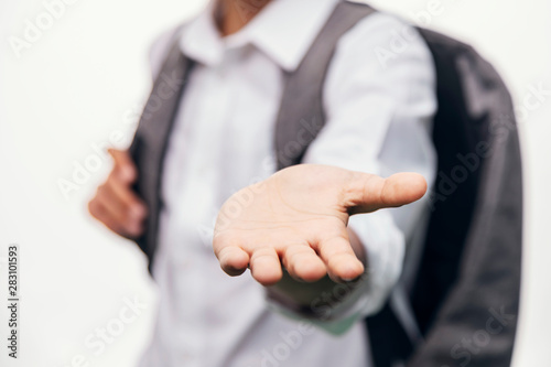 Schoolboy with backpack stretching hand with an opened palm