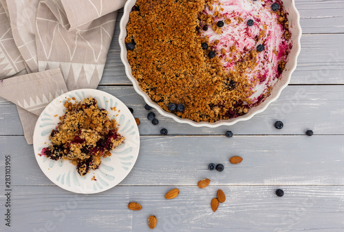 Crumble berry pie with blueberries and almonds on wooden background