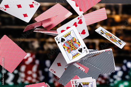 Red and Blue backed Playing cards cascading in front of a background of stacked poker chips