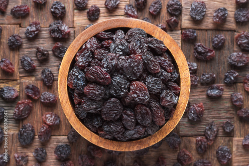 dried grapes, dark raisins in wooden bowl, top view. photo