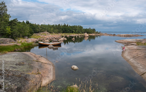 Fototapeta Naklejka Na Ścianę i Meble -  Northern nature, sea bay and wooden antique boat. Large stones on the bay and forest.