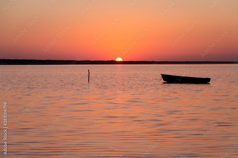 Reflection of boat with burning sky during sunrise/sunset