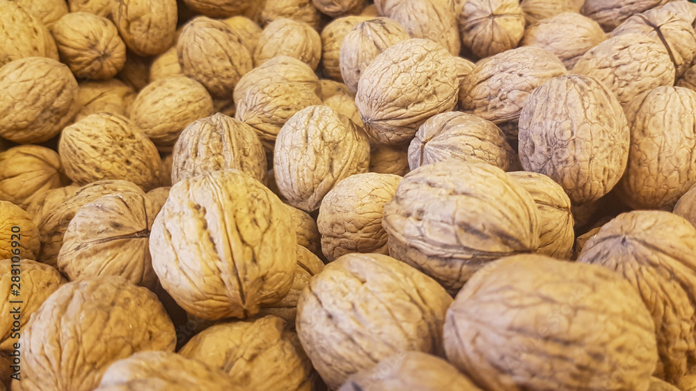 lots of brown inshell walnuts texture at the fresh vegan market