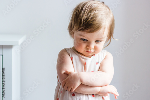 Bild auf Leinwand Sad toddler baby girl looking down with her arms crossed