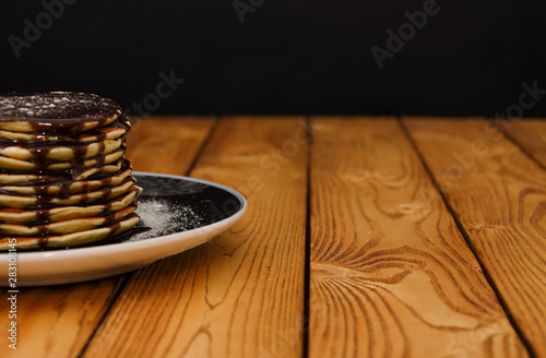 Fototapeta Naklejka Na Ścianę i Meble -  Pancakes with chocolade topping on the wooden background