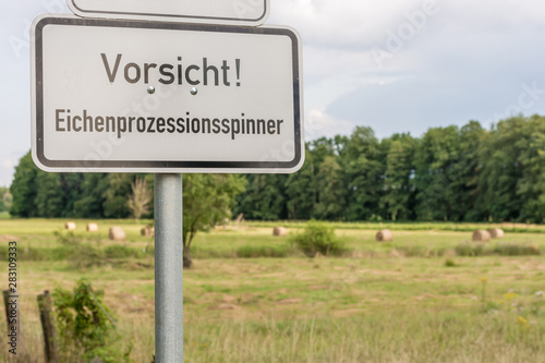 Warnung vor dem Eichenprozessionsspinner auf einem Schild mit der Aufschrift in deutscher Sprache Vorsicht Eichenprozessionsspinner