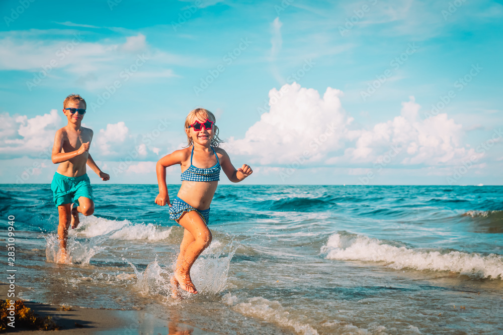 happy little girl and boy running at beach happy little girl and boy running at beach
