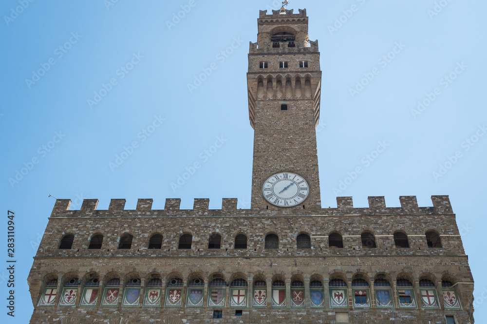 Facade of Pallazzo Vecchio, Florence, Italy with no people on sunny summer day.  Details of the coat of arms and famous clock tower can be seen