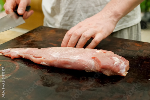 Cutting piece of pork meat on the table. Raw pork.
