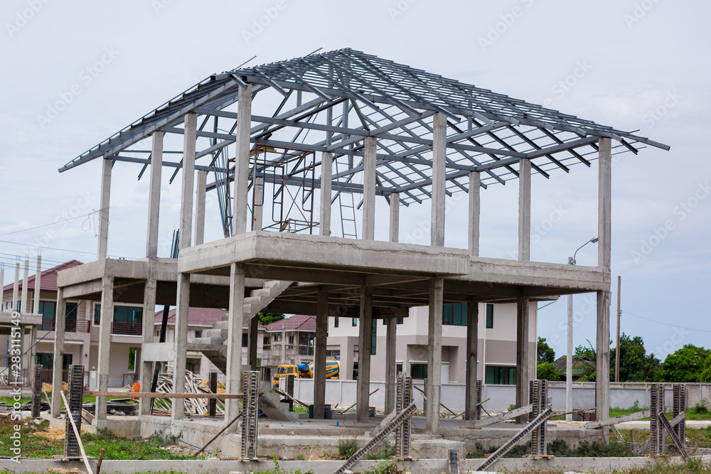 Home under construction using steel frames against. New residential construction home metal framing against. Building site with new homes under construction in Thailand.