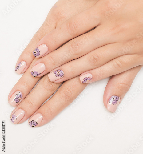 Beautiful flowers on a white lacquer on the nails on a multicolored background.
