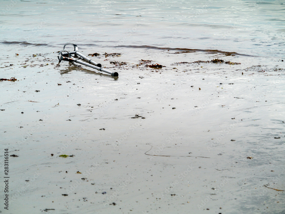 Old used crutches on a sand by water. Concept healthcare, Water