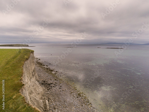 Wave breaker and pier, Spiddal, county Galway, Ireland, Burren in the background. Cloudy sky, Atlantic ocean. © mark_gusev