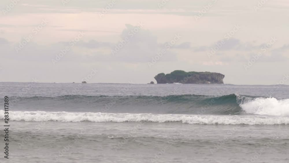 Cirlcling waves breaking near the coast with a small island in the background Cirlcling waves breaking near the coast with a small island in the background