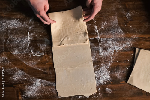 rolling out the dough with rolling pin on the table.