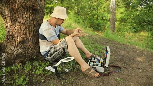 young caucasian scientist entomologist put a cricket on his arm and looks at how he crawls, close-up photo