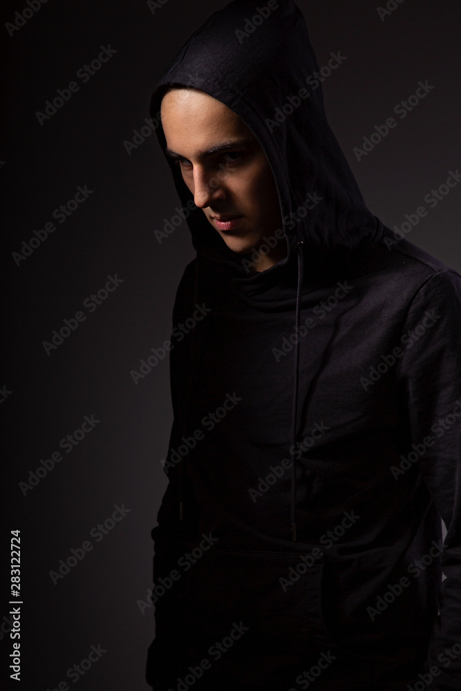 Mysterious serious man in black hoodie with hood on the head on dark  background. Dangerous criminal person in dark shadow. Stock Photo | Adobe  Stock