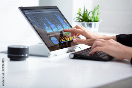 Businesswoman Analyzing Graph On Laptop At Workplace