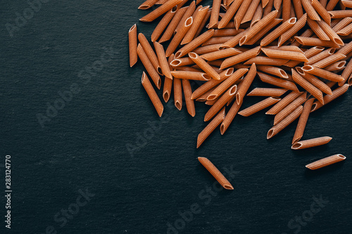 Whole penne scattered on dark slate - Beautiful pasta food background on black artesia stone photo