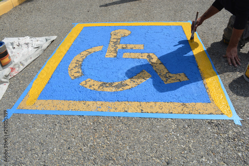 Painter repainting handicap parking on street pavement