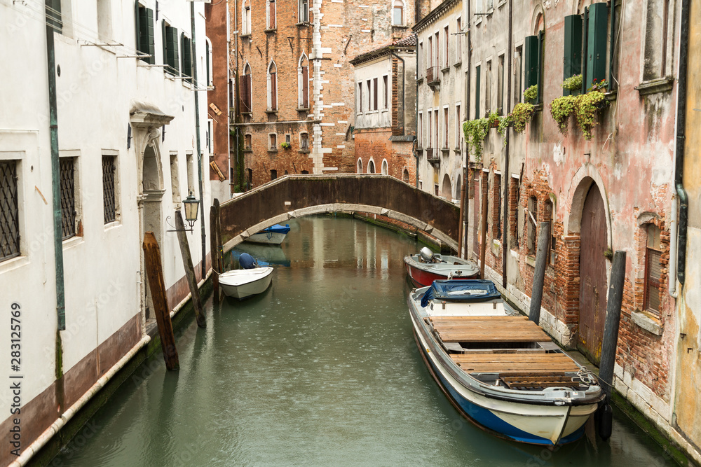 Narrow canal with boats in Venice