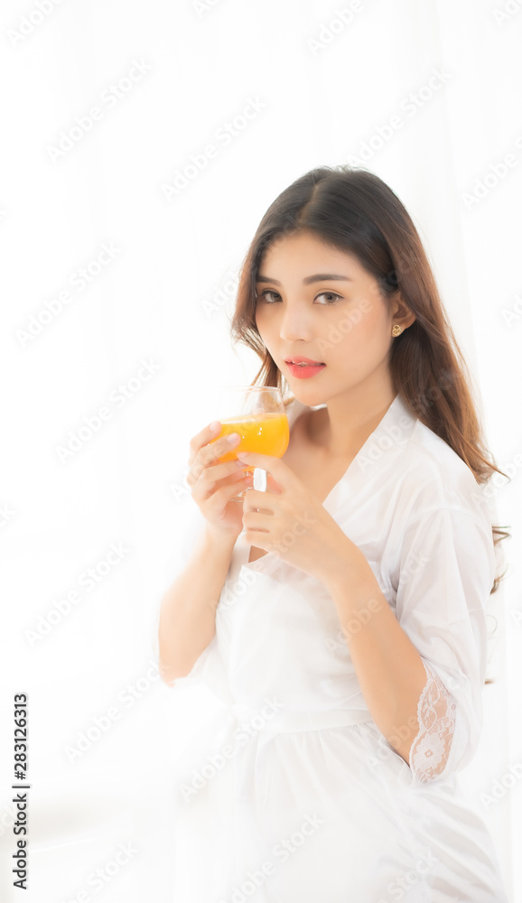 Portrait of a cute woman with brunet hair wearing white dress isolated over white background , drinking orange juice cocktail from a glass. Portrait of a cute woman with brunet hair wearing white dress isolated over white background , drinking orange juice cocktail from a glass.