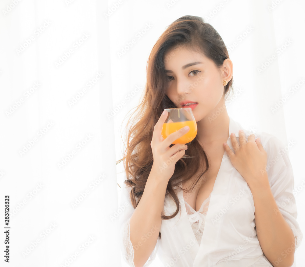 Portrait of a cute woman with brunet hair wearing white dress isolated over white background , drinking orange juice cocktail from a glass. Portrait of a cute woman with brunet hair wearing white dress isolated over white background , drinking orange juice cocktail from a glass.