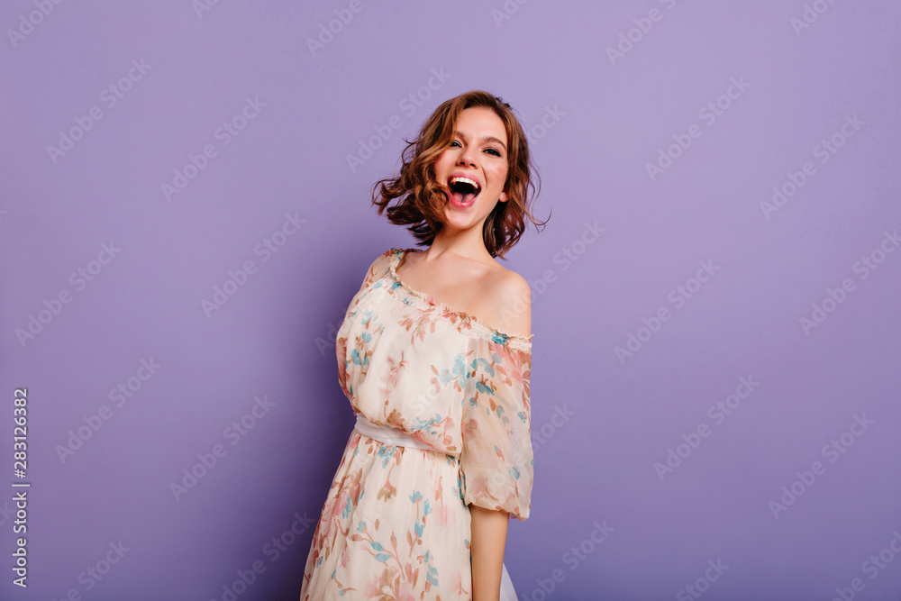 Sensual white woman in summer dress laughing on purple background. Charming female model in romantic clothes smiling during indoor photoshoot. - obrazy, fototapety, plakaty 