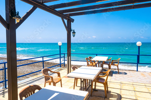 Island of Cyprus. Cafe on the Mediterranean sea. Tables near the sea. Holidays in Cyprus. Turquoise water. Pebbles on the beach. Lunch with sea view.