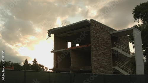 A building in the process of being deconstructed silhouetted against a sunset sky