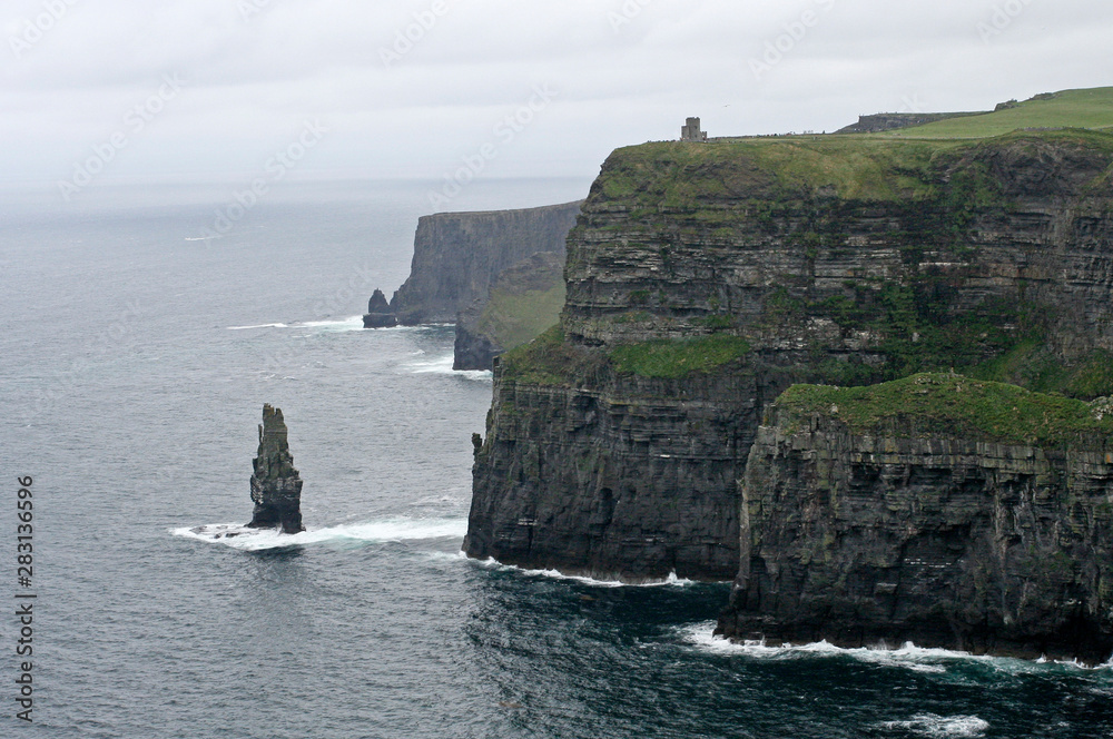 High grassy cliffs and the small separate cliff on the sea coast and heavy fog in the summer High grassy cliffs and the small separate cliff on the sea coast and heavy fog in the summer