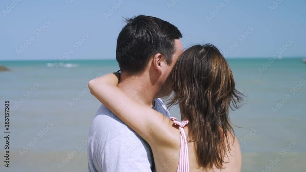 Happy young man and woman hugging on the beach, near a boat is tied, vacation concept Happy young man and woman hugging on the beach, near a boat is tied, vacation concept