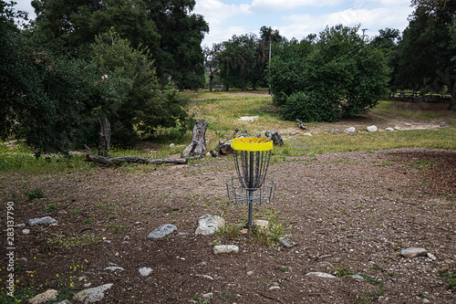 open dry natural park with california live oak trees, rocks, and grass weeds and frisbee golf net photo