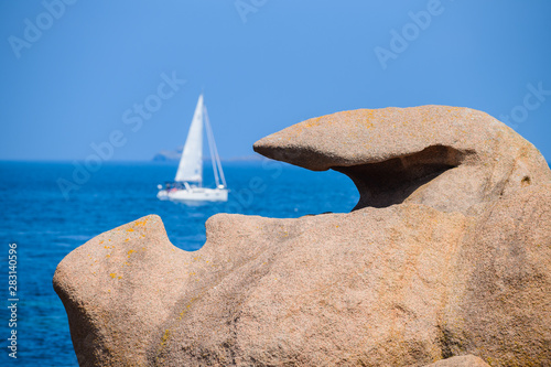 Seascape with huge pink granite boulders and a yacht near Plumanach. The coast of pink granite is a unique place in Brittany. France photo