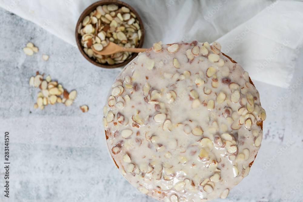 almond olive oil cake with brown butter icing and sliced almonds, dripping icing on cake, marble and wood cake stand, styled bakery almond olive oil cake with brown butter icing and sliced almonds, dripping icing on cake, marble and wood cake stand, styled bakery