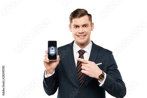 happy businessman in suit pointing with finger at smartphone with gdpr lettering on screen isolated on white