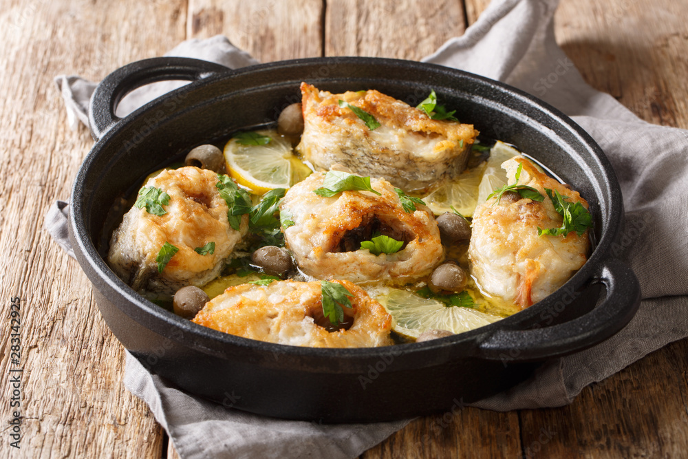 Healthy food cod fish baked with lemon and olives in a spicy sauce close-up in a pan. horizontal