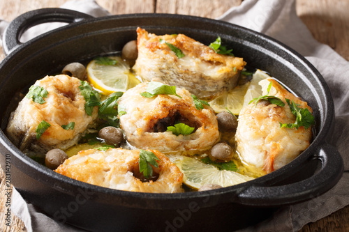 Mediterranean pieces of cod baked with lemon and olives close-up in a pan. horizontal