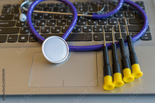 Screwdrivers on a laptop. Stethoscope on laptop keyboard. Health care or IT security concept. Laptop repair concept. Computer repair concept Close-up view. Hardware