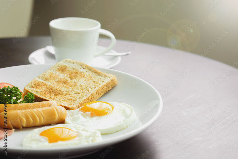 American breakfast and hot coffee in a white ceramic coffee cup on a wooden table with warm morning sunshine and lens flare background. American breakfast and hot coffee in a white ceramic coffee cup on a wooden table with warm morning sunshine and lens flare background.