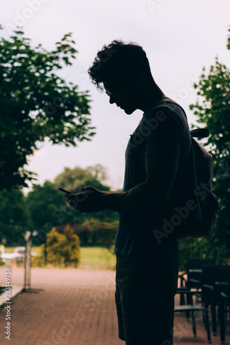 side view of man with backpack using digital device outside