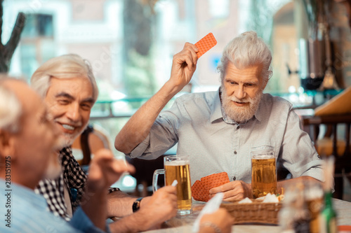 Grey-haired active men gambling while drinking beer