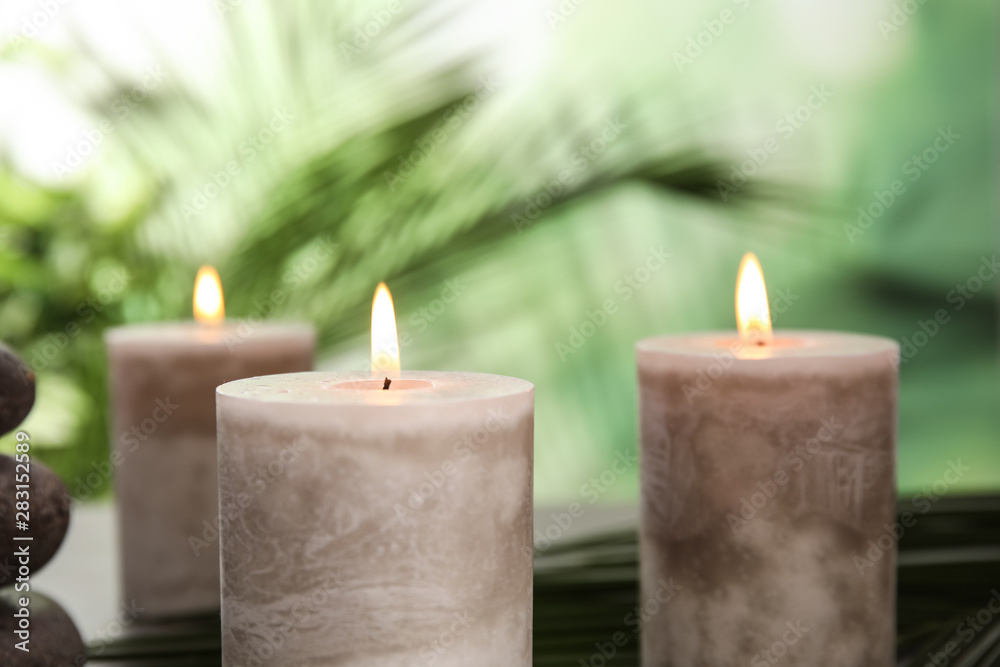Burning aromatic candles on blurred green background Burning aromatic candles on blurred green background
