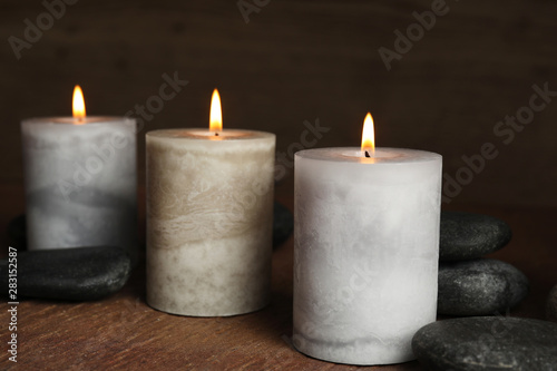 Burning candles and spa stones on wooden table