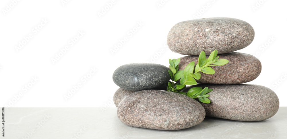 Stack of spa stones and leaves on table against white background. Space for text Stack of spa stones and leaves on table against white background. Space for text