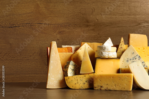 Different types of delicious cheese on table against wooden background
