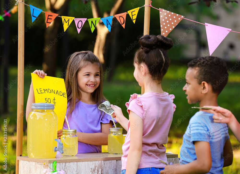 Little girl selling natural lemonade to kids in park. Summer refreshing