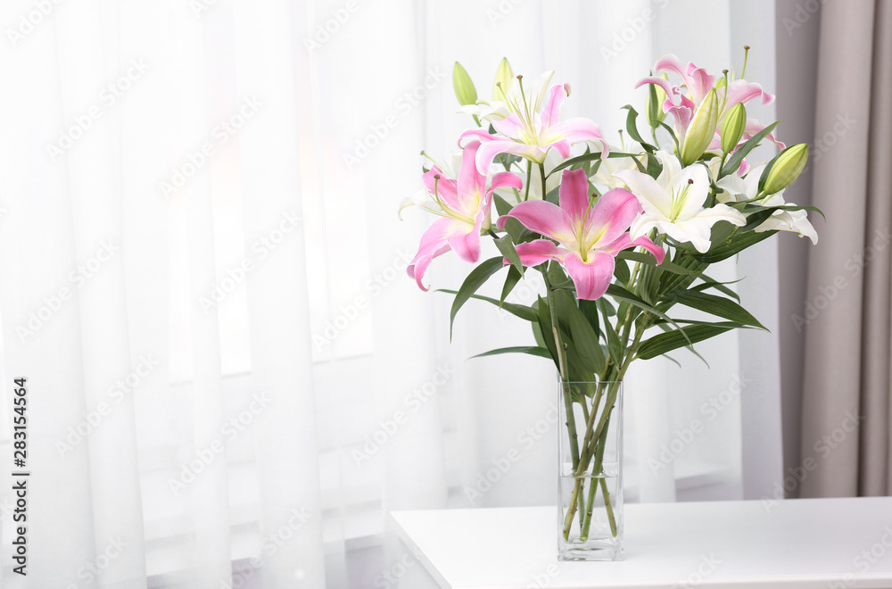 Vase with bouquet of beautiful lilies on white table indoors. Space for text Vase with bouquet of beautiful lilies on white table indoors. Space for text