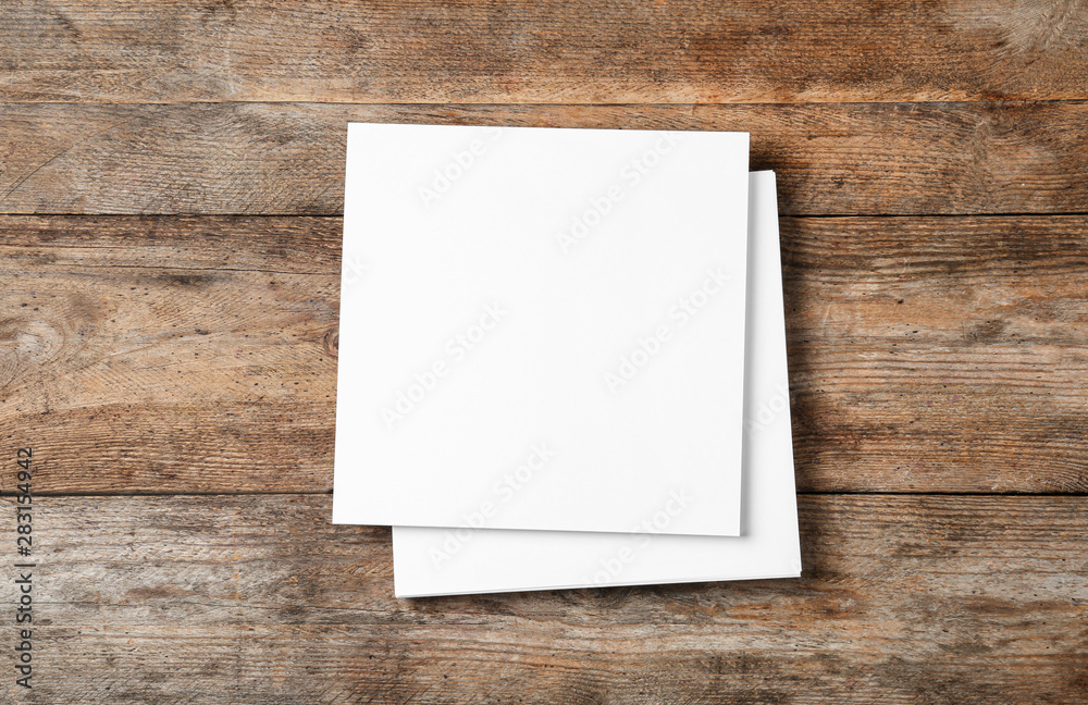 Stack of blank paper sheets for brochure on wooden background, top view. Mock up Stack of blank paper sheets for brochure on wooden background, top view. Mock up